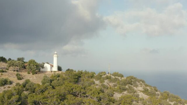 Gelidonya lighthouse on a background of mountains. Beautiful ladscape with green trees. Drone footage 4K