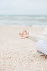 Young caucasian girl meditate at the beach, doing yoga lotus pose, child meditation outdoors