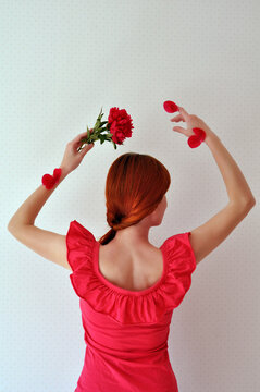 Redhead girl dancing with a red peony and petals on her hands