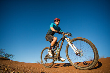 Naklejka na ściany i meble Wide angle view of a mountain biker speeding downhill on a mountain bike track.