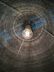 The electric lamp shines in a metal mesh shade