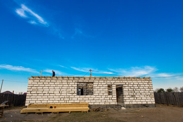 Construction site of a house under construction. Unfinished walls of the house made of white aerated concrete blocks of autoclave type. Project of a single-storey house.