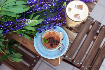Coffee and tiramisu on the table on the veranda of the coffee shop
