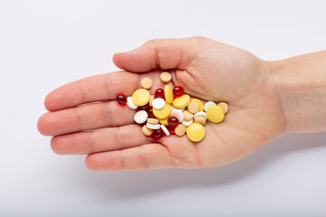 Top view of pills in hand on white background. A hand hold the pills and drugs top view close up