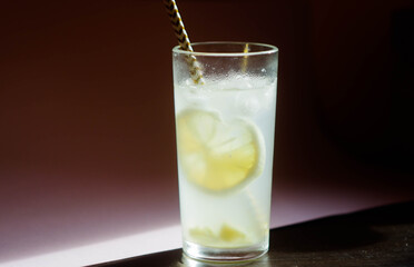Lemonade in glass with ice cubes. Summer party refreshing drink. Lemon peel and ginger root. Copy space 