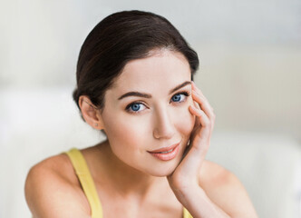Naklejka premium Beautiful young woman portrait. Smiling girl looking at camera and enjoying life at home. Beauty, relaxation, wellbeing concept