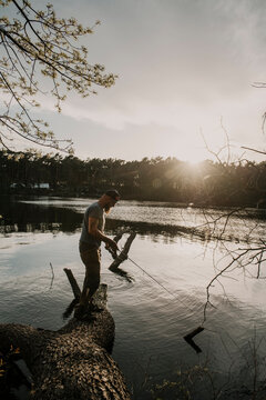 Europe, Germany, Berlin, Mueggelheim, Grosse Krampe lake, fishing on a trunk.
