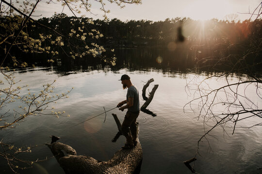 Europe, Germany, Berlin, Mueggelheim, Grosse Krampe lake, fishing on a trunk.