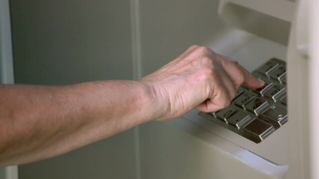 Senior woman's hands at a bank machine