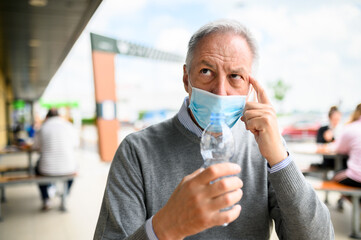 Man trying to drink a bottle of water wearing a mask, funny coronavirus concepy