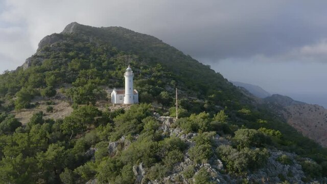 A young man waving in the background of lighthouse. Natural landscape. Gelidonya, Adrasan. Drone footage 4K