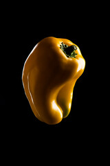 Yellow bell peppers lit on black background