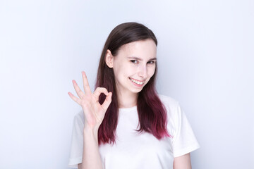 Young woman showing ok gesture and smiles, gray background