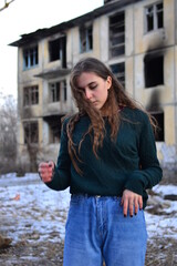a sad girl stands near her house after a fire
