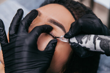 master girl in a beauty salon makes eyelashes permanent