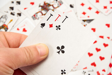 Playing cards in hands on a background of scattered cards.