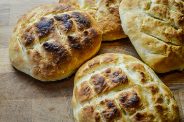 Little italian focaccia breads homemade and freshly cooked on a wooden table close up. The focaccia is a traditional italian oven baked flat bread.