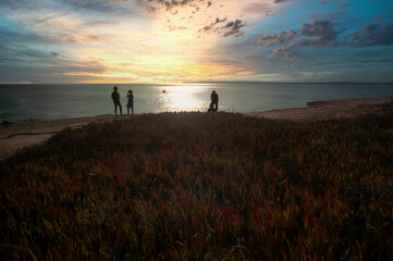 Fototapeta na wymiar Group of friends watching the sunset at a beach of Formentera island, Mediterranean sea, Spain
