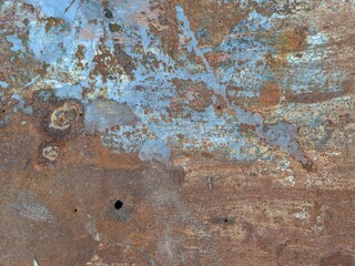 the texture of rusty metal with nail holes and peeling paint.
