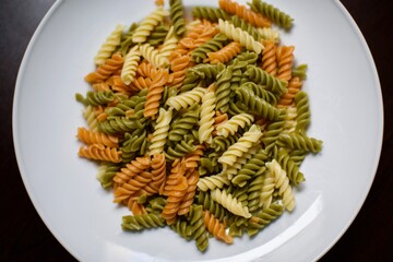Vegetables pasta. Yellow, green and orange colors with white porcelain plate. Close up view.