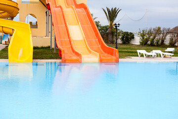 Closed water slides are in aquapark, calm water surface of swimming pool, empty resort area
