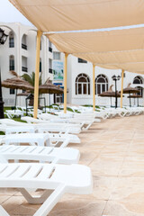A lot of empty white plastic sun loungers are on terrace of a hotel area, cancelled holiday season due to coronavirus