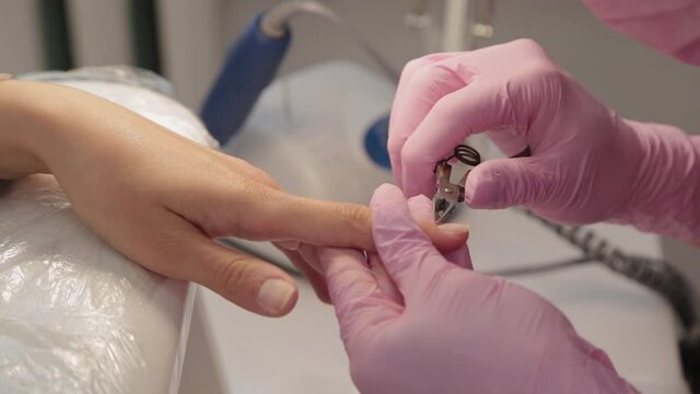 Manicurist removes cuticles with forceps.