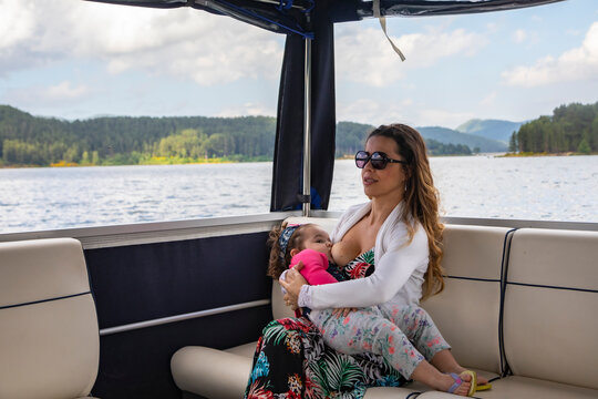 
young mother breastfeeding a baby during boat trip on the lake
