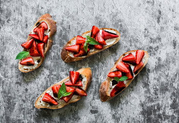 Bruschetta, sandwiches with strawberries, cream cheese and balsamic sauce on a grey background, top view. Delicious appetizer, tapas