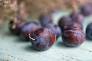 Fototapeta premium Plum. Fresh plum. Harvest. Autumn harvest. Autumn. Blue plums. Fresh plums on a wooden surface. Fresh plums on wooden table background.