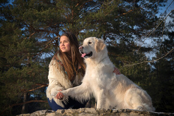 Cheerful pretty young woman and hugging her dog on a winter walk. Friendship. 