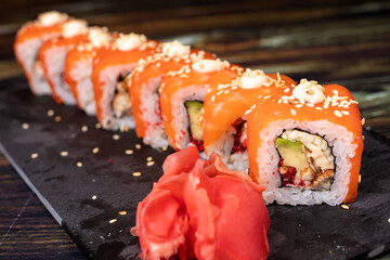Sushi with salmon and rice with sesame seeds on a black background. Rolls, Japanese national cuisine, raw fish.