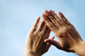 Human Hands blocking sunlight and pointing at blue sky