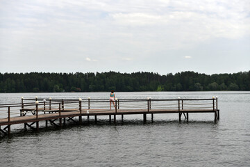 Obraz premium woman looks at sports exercises on the river from the pier