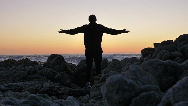 Young men warrior monk practicing silhouette tai chi karate kung Fu on the rocky stones horizon at sunset or sunrise. Art of self-defense. Silhouette on a background of dramatic epic waves
