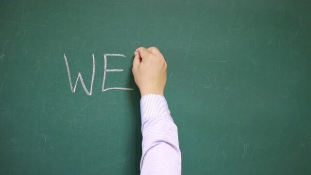 Hand writes WELCOME on a blackboard
