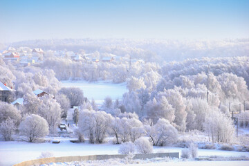 Beautiful winter landscape - country houses, field, lake and trees covered with white snow against...