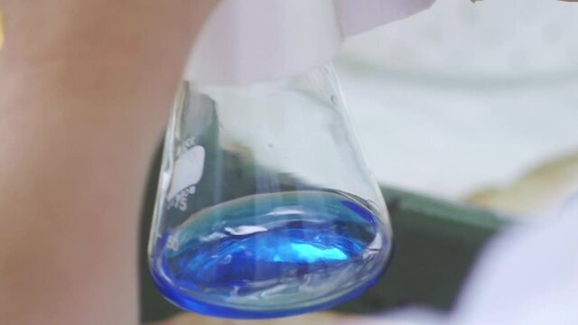 Erlenmeyer flask in laboratory,  processing of the laboratory sample in an Erlenmeyer flask, titration with reagent from a burette, very close up