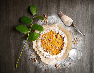 French pie whit nut, sugar, green plant and peach on the brown background
