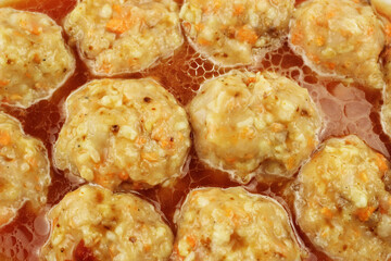 Raw meatballs in gravy in a baking container