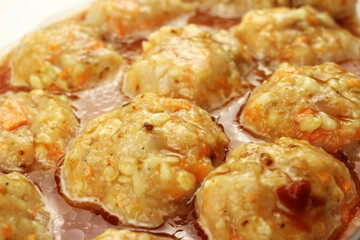 Raw meatballs in gravy in a baking container
