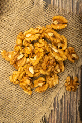 Fototapeta premium Peeled walnuts in bulk on a wooden table covered with rough-textured burlap. Healthy diet. Fitness diet. Close up.