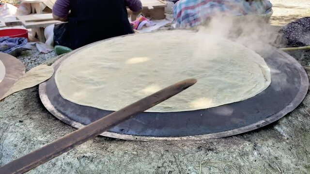 Traditional turkish  bread. Also known as "yufka ekmek" ,  natural organic homemade yufka bread. Woman cooking the handmade bread on wood fire.