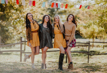 Young pretty women of four posing at the outdoor pumpkin's market place. Autumn background.