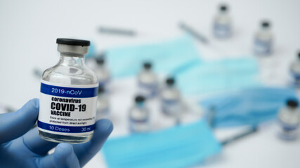 Fototapeta premium Covid-19 Corona Virus 2019-ncov Vaccine vials medicine drug ampoule bottle closeup syringe injection medical nitrile gloves mask glasses. Vaccination, treatment to cure Covid 19 Corona Virus infection