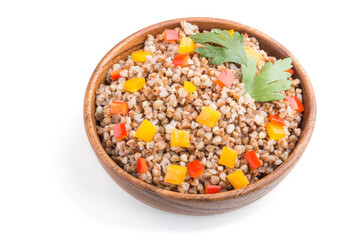 Buckwheat porridge with vegetables in wooden bowl isolated on white background. Side view, close up.