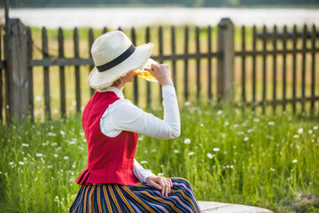 Fototapeta premium Woman drinking beer on a bench. Ligo folk.
