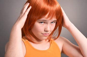 Naklejka premium Portrait of cute girl with red hair posing in studio