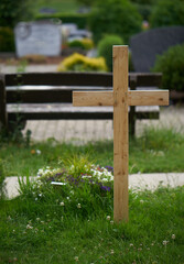 fresh cross at graveyard corona covid germany park bench in backround