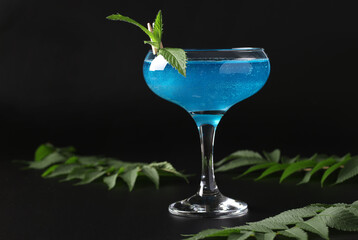 Shimmer edible glitter sparkling blue wine with garnish mint on black background. Space for text